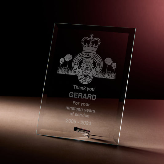 Glass display plaque with engraved dedication and crest photographed on a dark, softly lit background