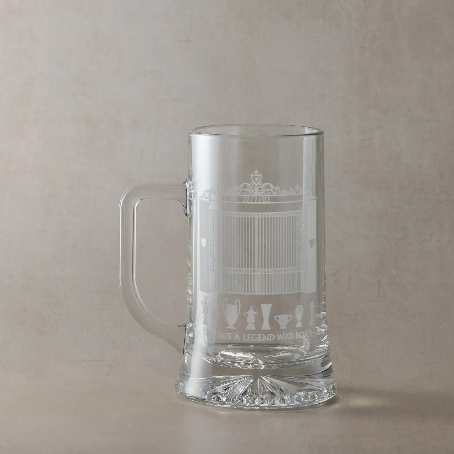 Engraved tankard featuring a line-art interpretation of Anfield's Shankly Gates with football trophy silhouettes, photographed on a beige background.