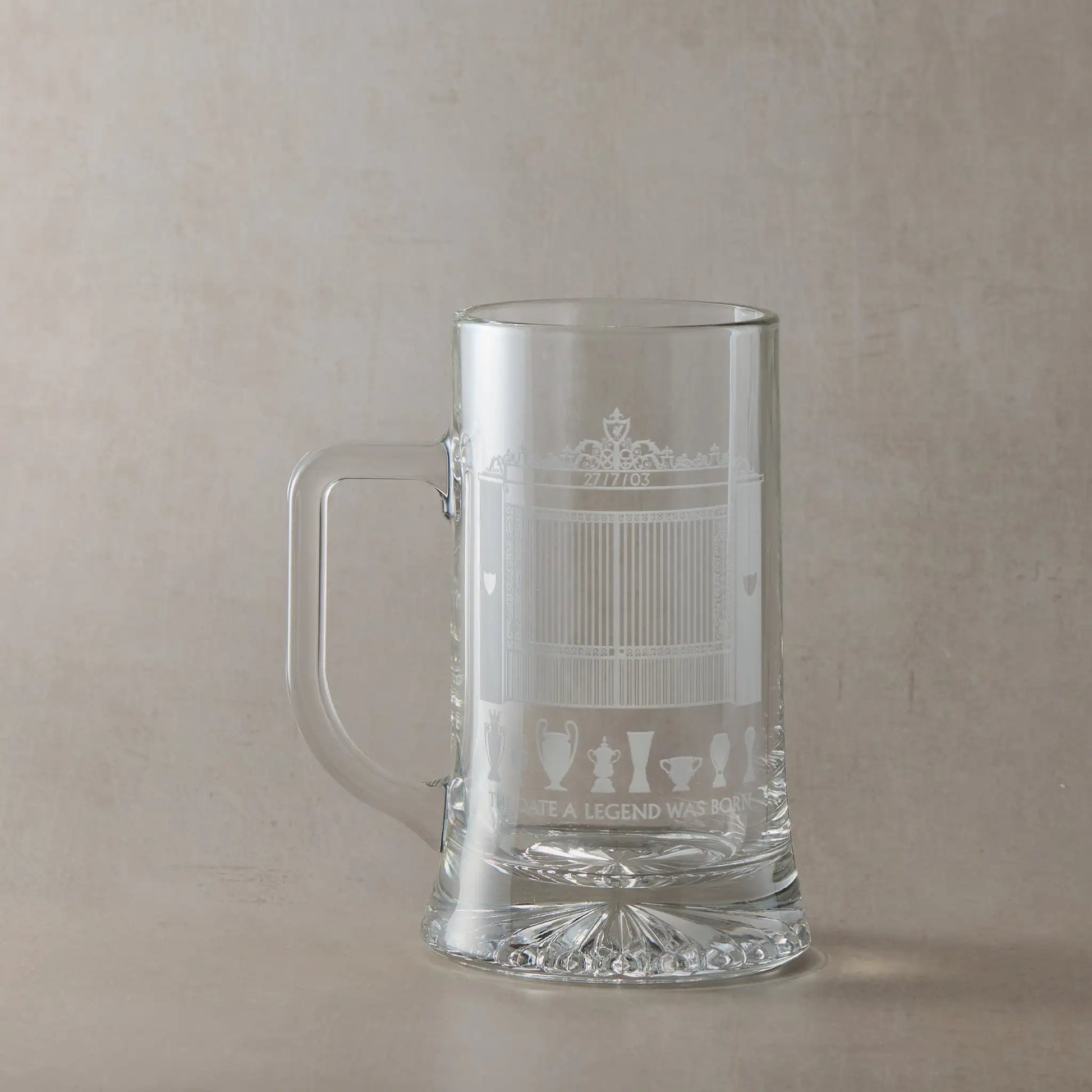 Engraved tankard featuring a line-art interpretation of Anfield's Shankly Gates with football trophy silhouettes, photographed on a beige background.