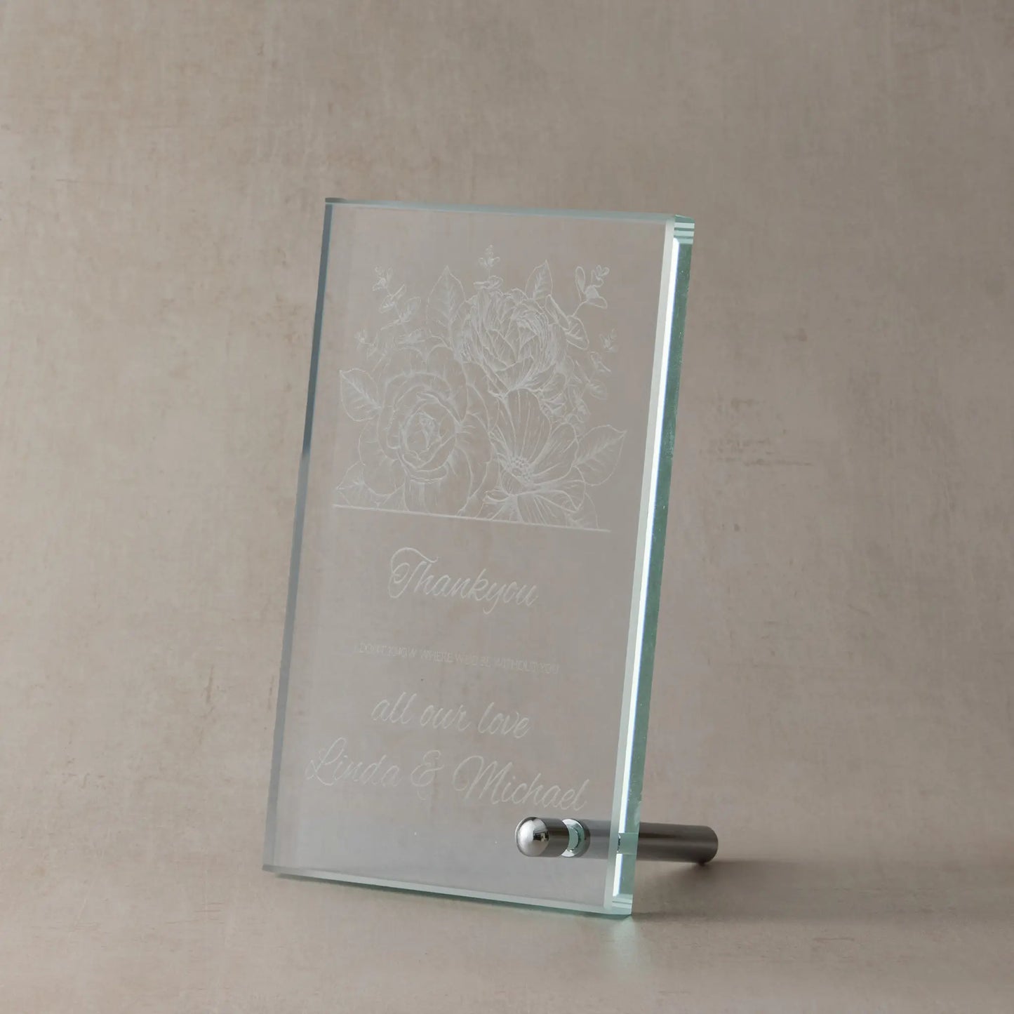 Glass plaque with floral design and engraved thankyou text on a dark background