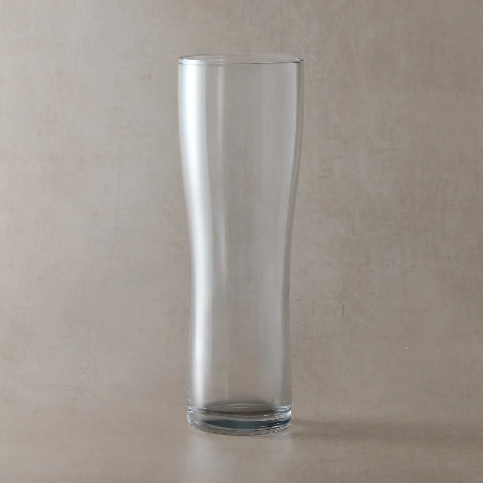 Clear pint glass on a beige background