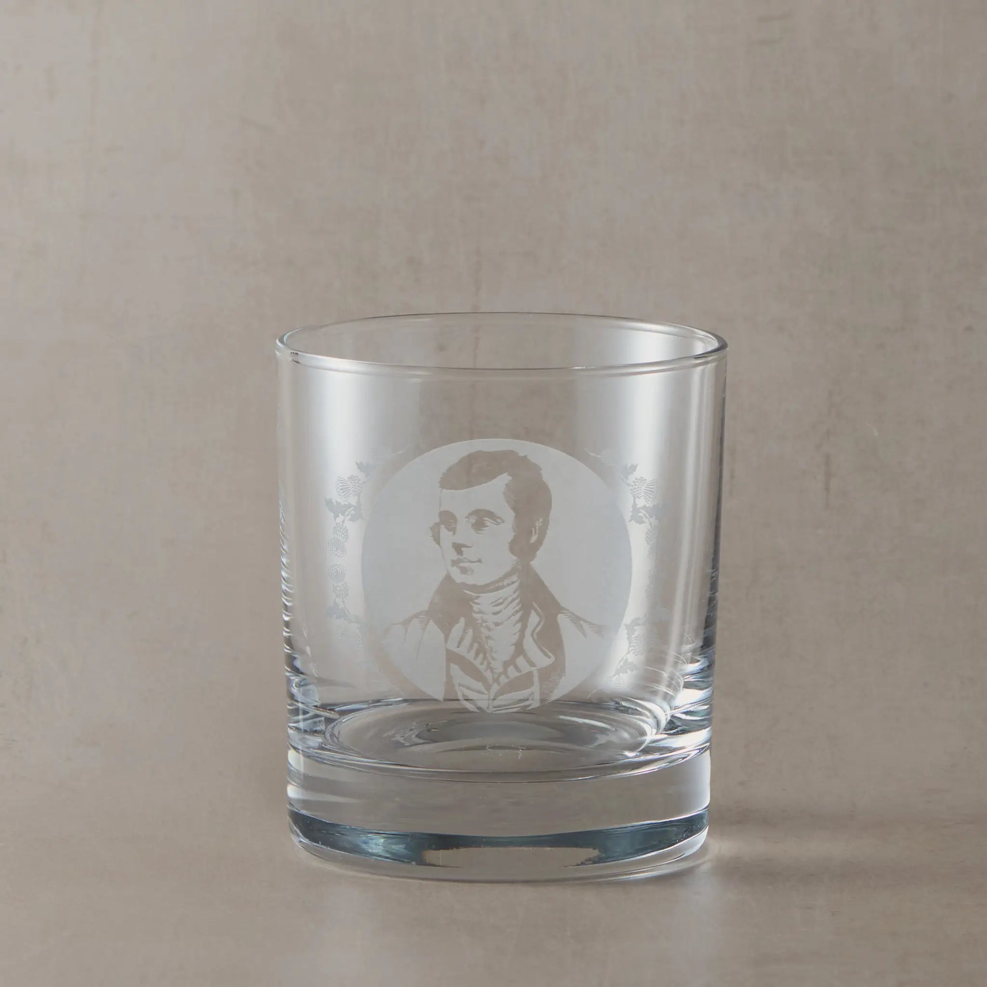 Portrait of the Scottish poet Robert Burns engraved into a whisky glass with thistle design