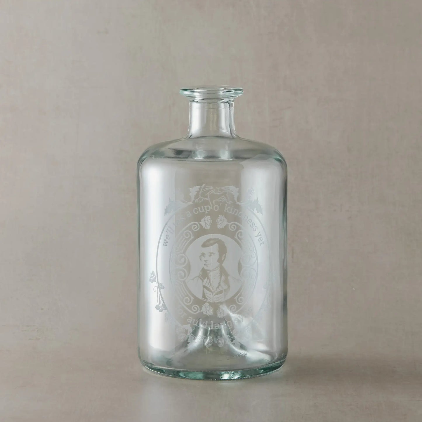 Apothecary decanter engraved with the Poet Robert Burns, roses and a mouce, photographed on a beige background