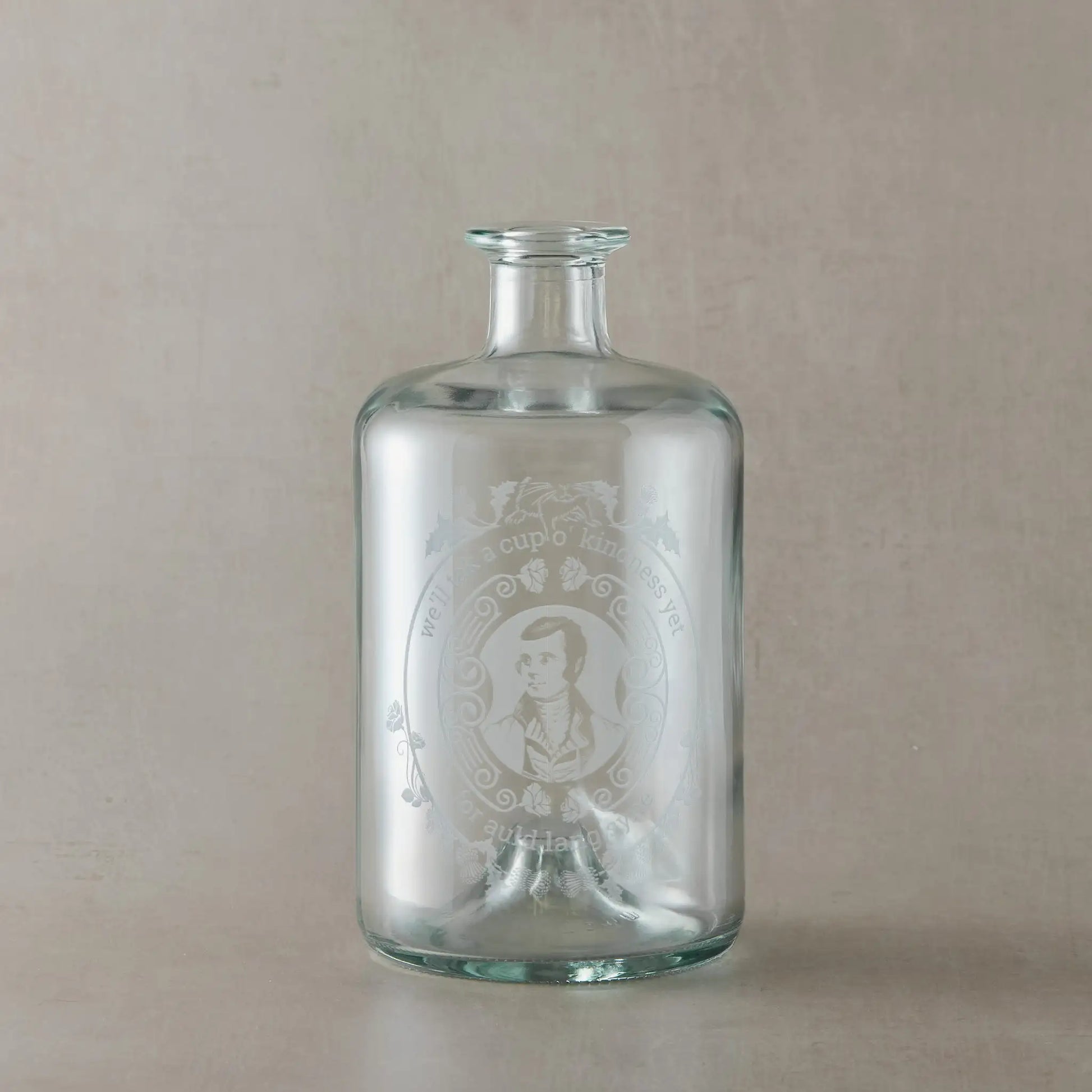 Apothecary decanter engraved with the Poet Robert Burns, roses and a mouce, photographed on a beige background