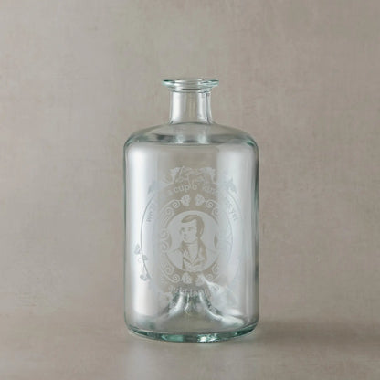 Apothecary decanter engraved with the Poet Robert Burns, roses and a mouce, photographed on a beige background