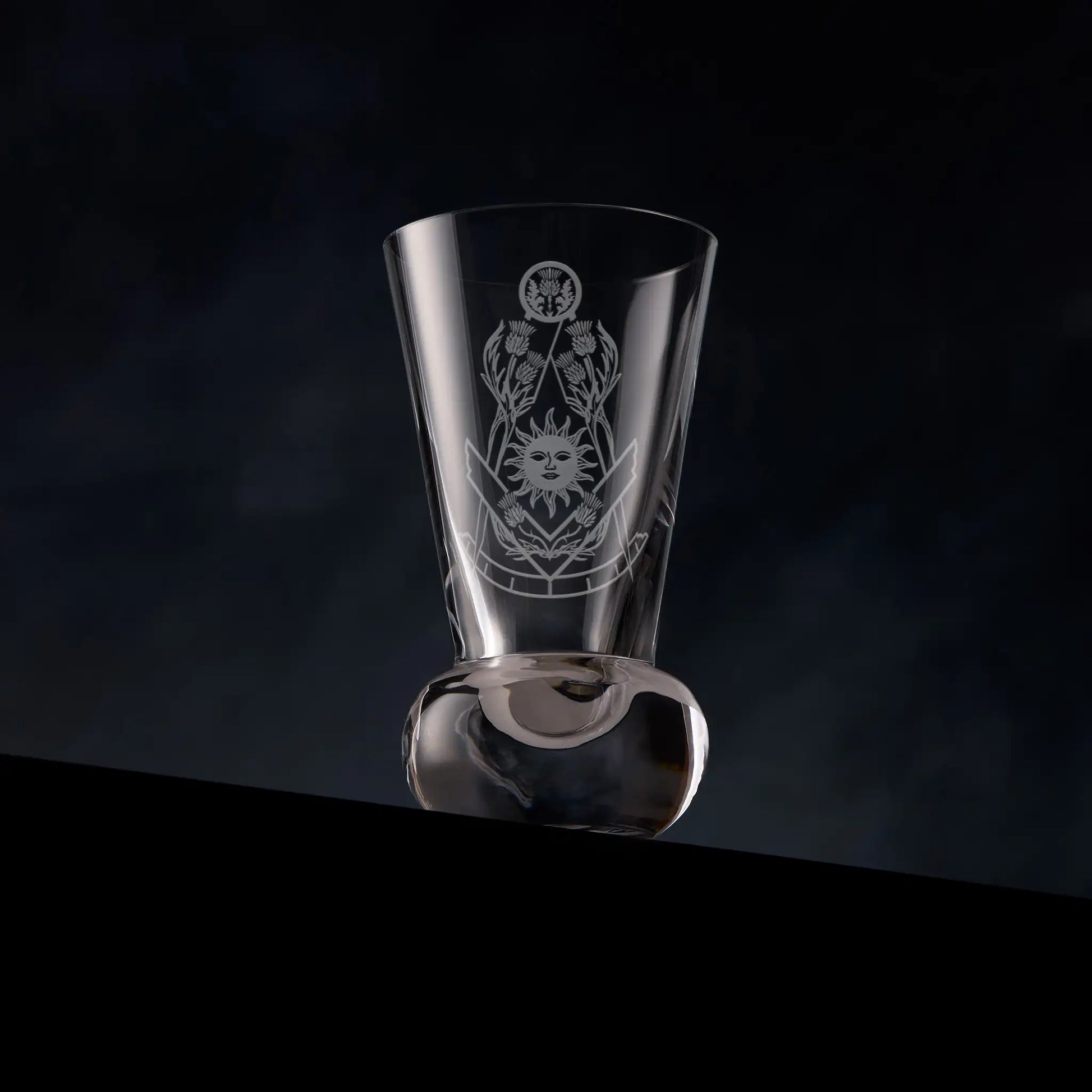 Masonic firing glass engraved with thistles and square and compass design of the right worshipful master on a dark background