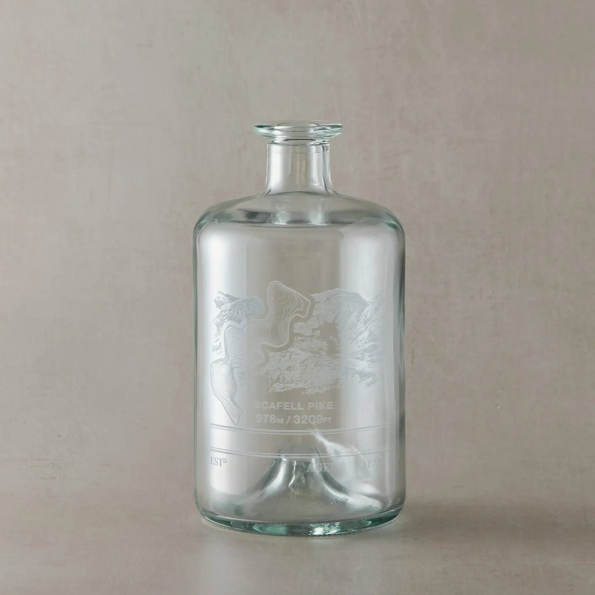 Glass apothecary decanter bottle with engraved Scafell Pike mountain design on a beige backround