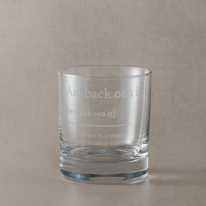 Whisky glass engraved with the Scottish phrase “Am Back Oan It” on a black background.
