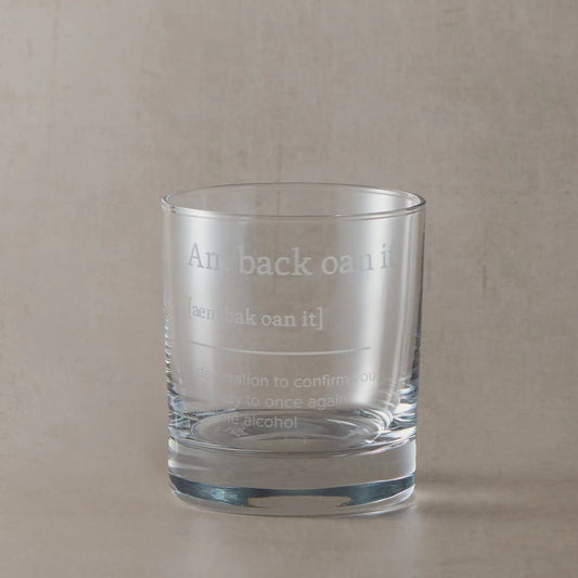 Whisky glass engraved with the Scottish phrase “Am Back Oan It” on a black background.