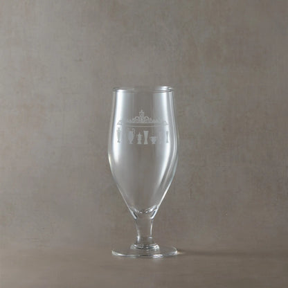 Stemmed beer glass engraved with the shankly gates and tropies, shown on a beige background