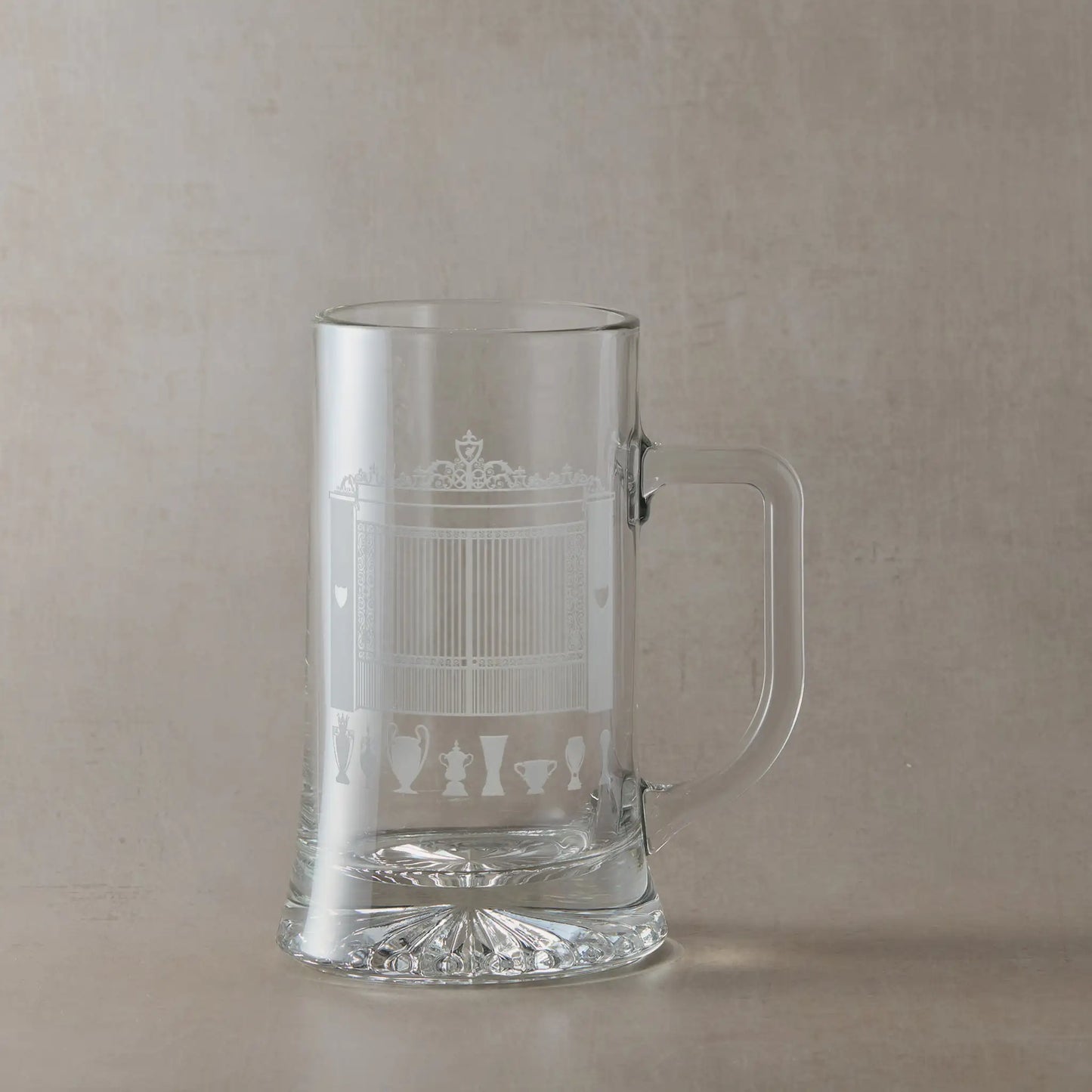 Tankard engraved withof Anfield's Shankly Gates with football trophy silhouettes, photographed on a beige background.