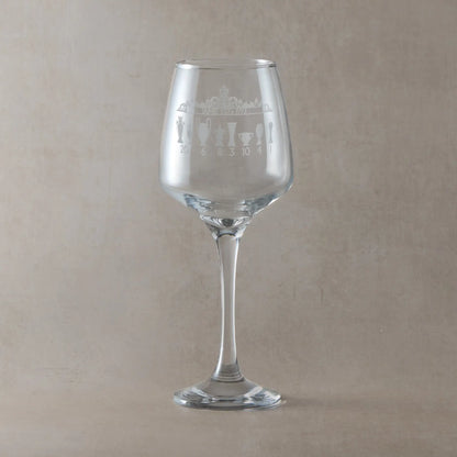 Clear wine glass with engraved trophy design on a beige background