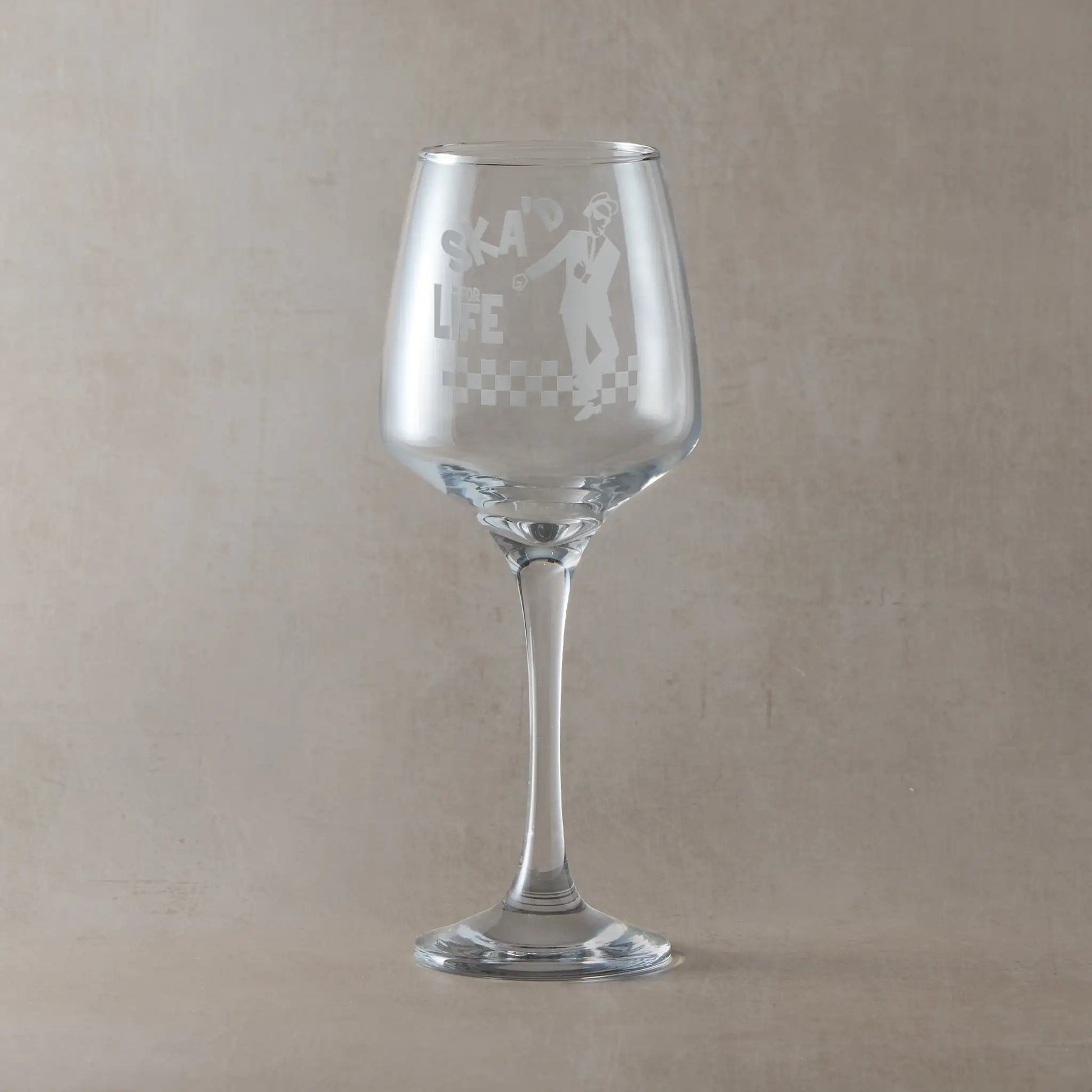 Wine glass with Walt Jabsco and checkerboard engraving and SKA'd for Life text, on a beige background