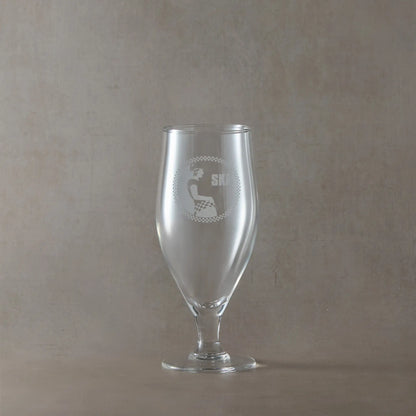 Stemmed eer glass engraved with SKA rude girl surrounded by a checkerboard design, shown on a beige background