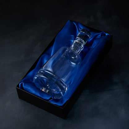 Handmade glass spirit decanter on blue satin fabric in a black presentation box against a dark background
