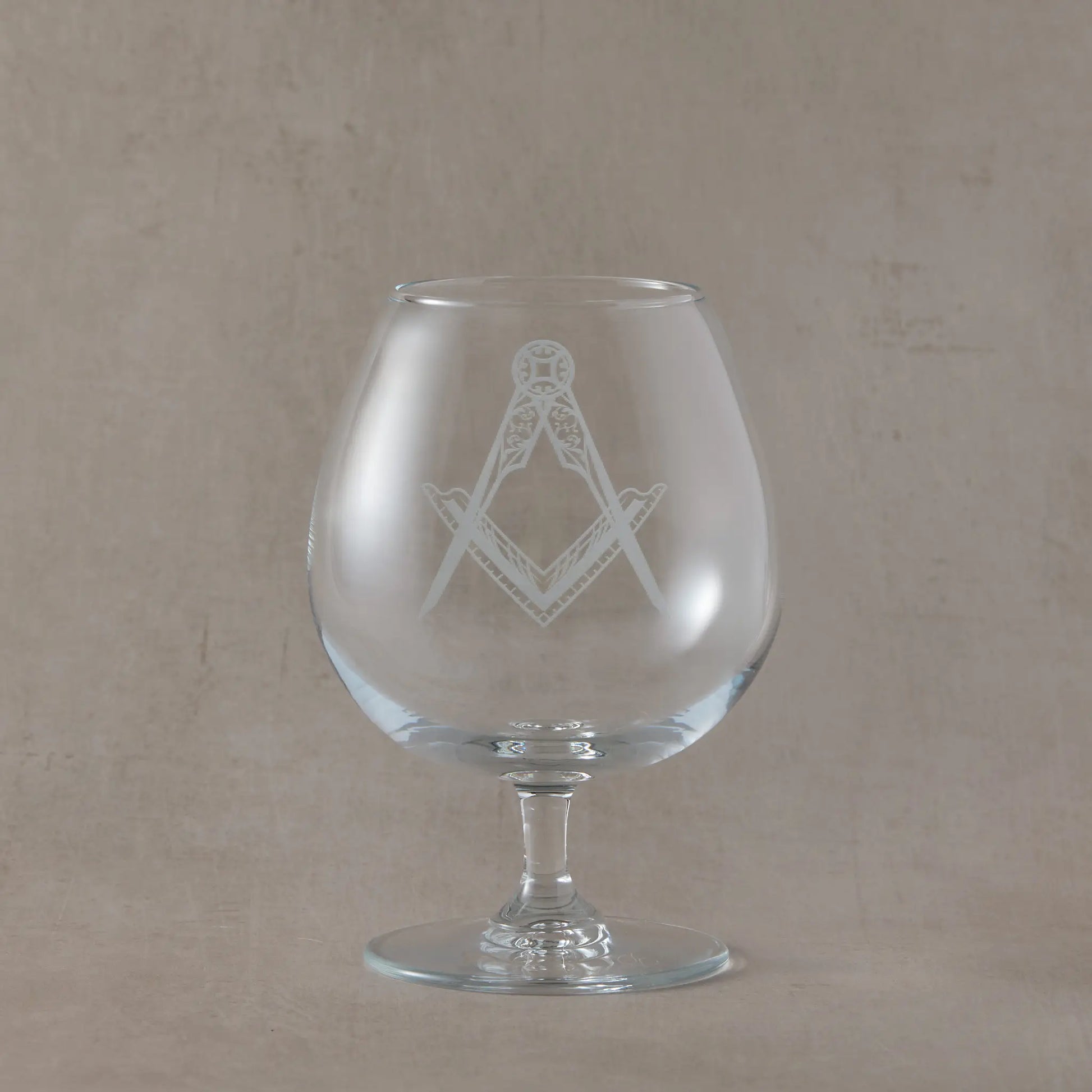 Brandy glass with Masonic square and compass symbol on a beige background