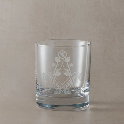 Masonic whiskey glass with Square & Compass, Lion rampant, and roses on a beige background