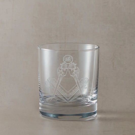 Whisky glass engraved with square and compass entwined with daffodils on a beige background