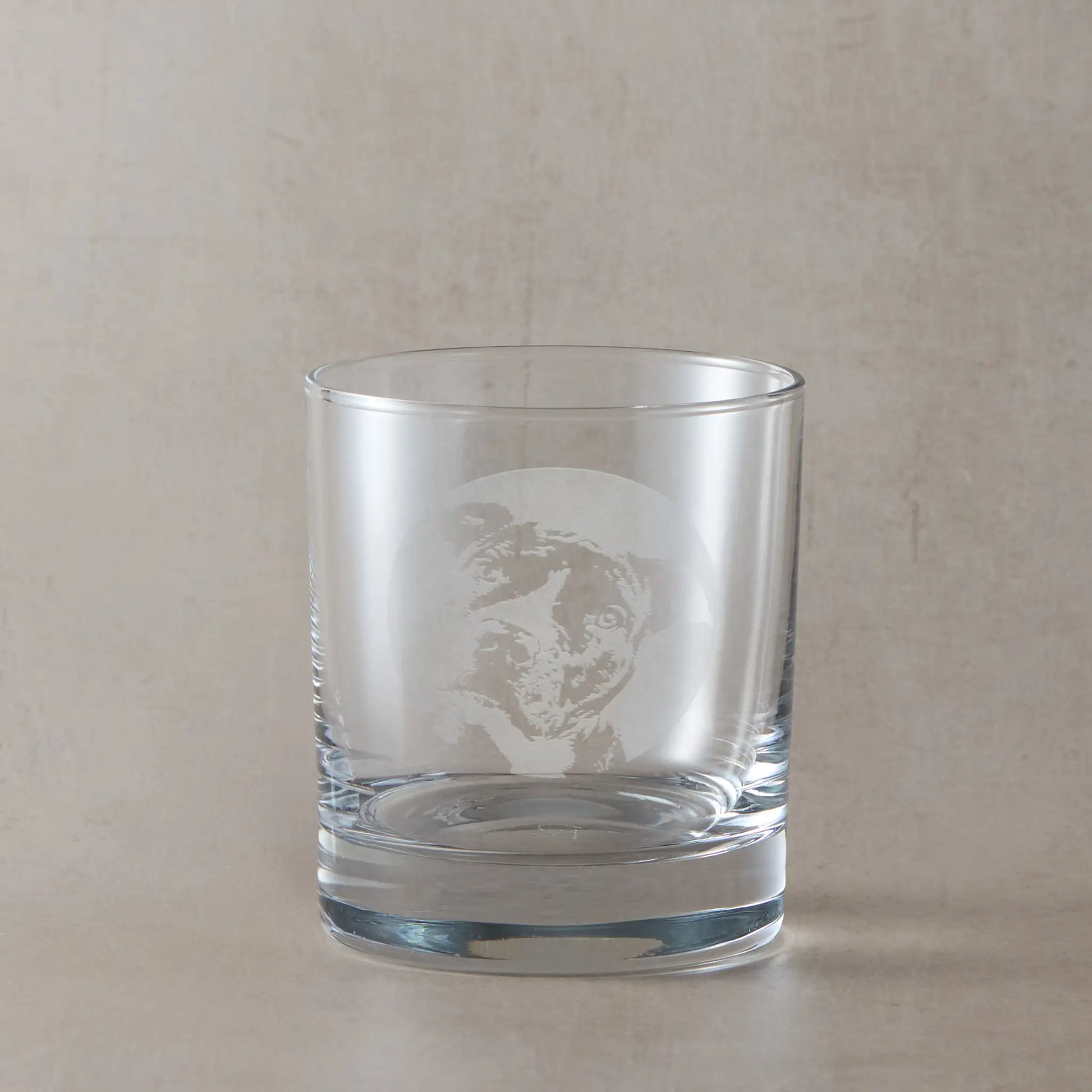 Whisky glass with engraved portrait of a Staffordshire Bull Terrier, on a beige background
