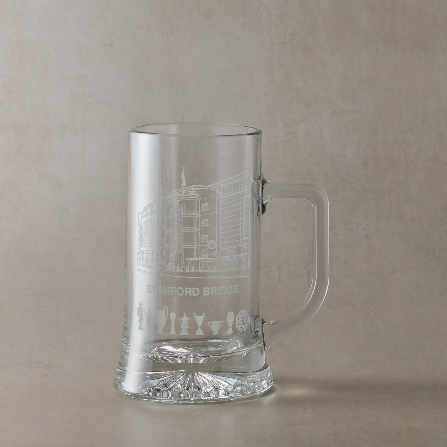 Engraved beer tankard showing Stamford Bridge stadium façade in Chelsea with trophy silhouettes beneath.