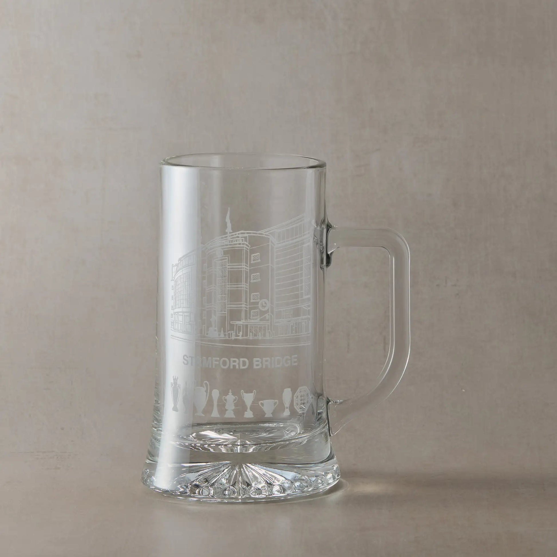 Engraved beer tankard showing Stamford Bridge stadium façade in Chelsea with trophy silhouettes beneath.