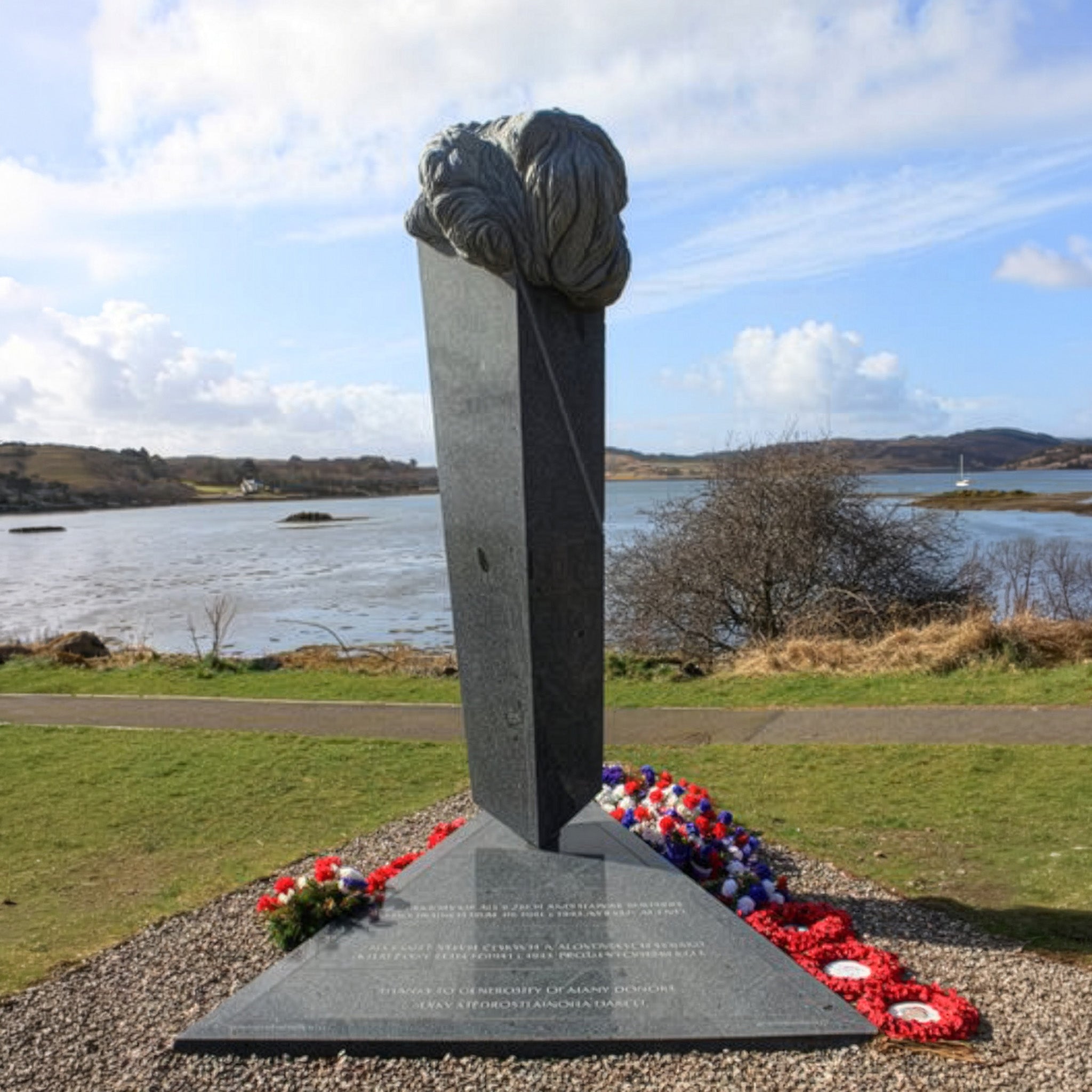 Memorial sculpture with a knot design in front of a body of water