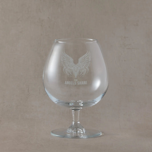 Brandy glass with angel wings and 'The Angels Share' text on a beige background