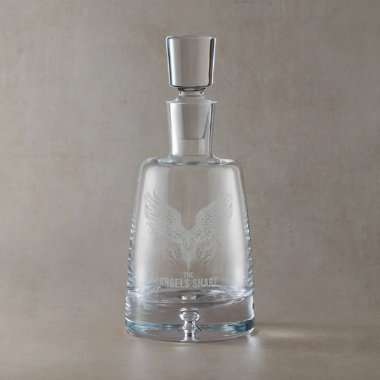 Engraved decanter with The Angels Share wing design on a beige background