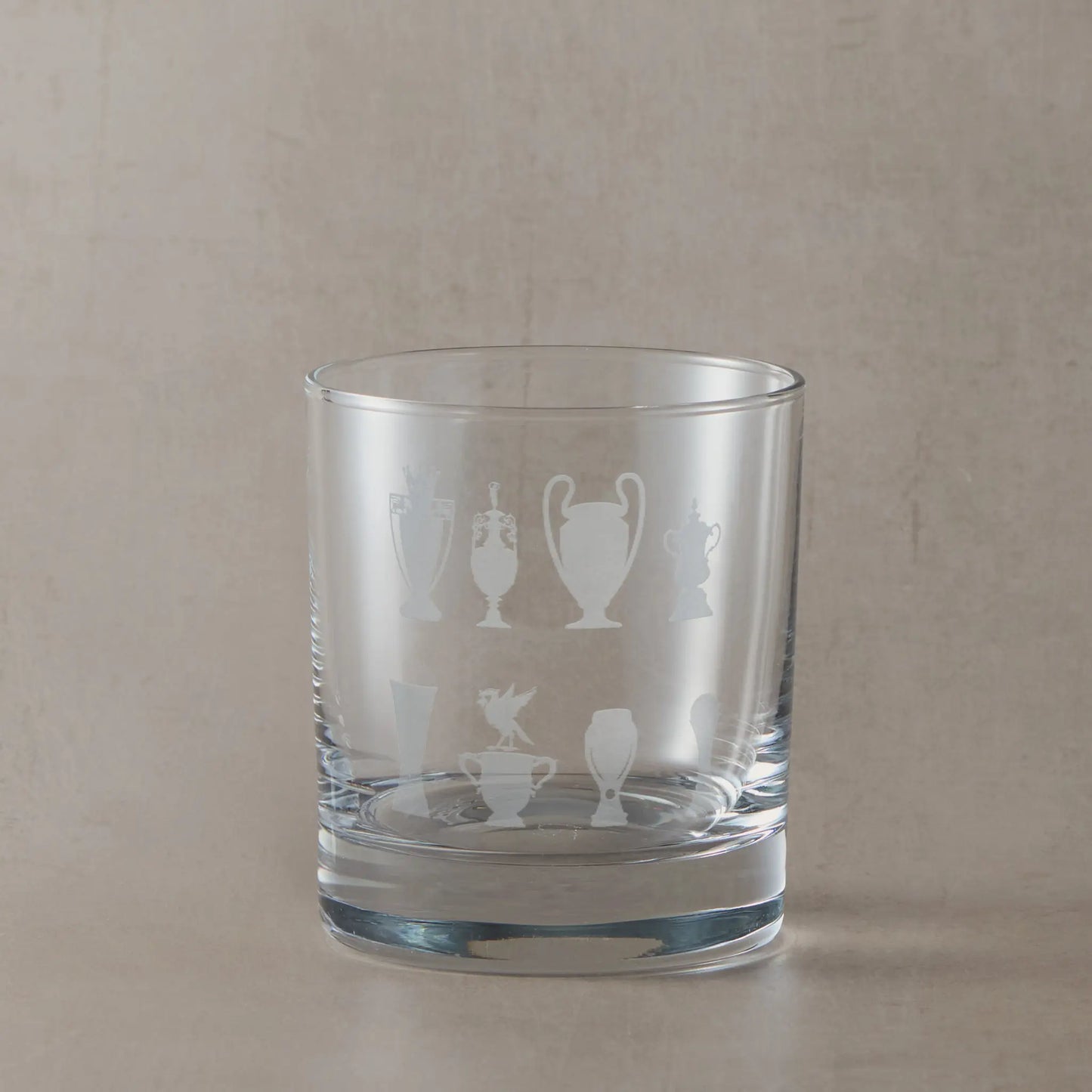 Whisky glass engraved with honours wall trophy silhouettes and liverbird photographed on a beige background