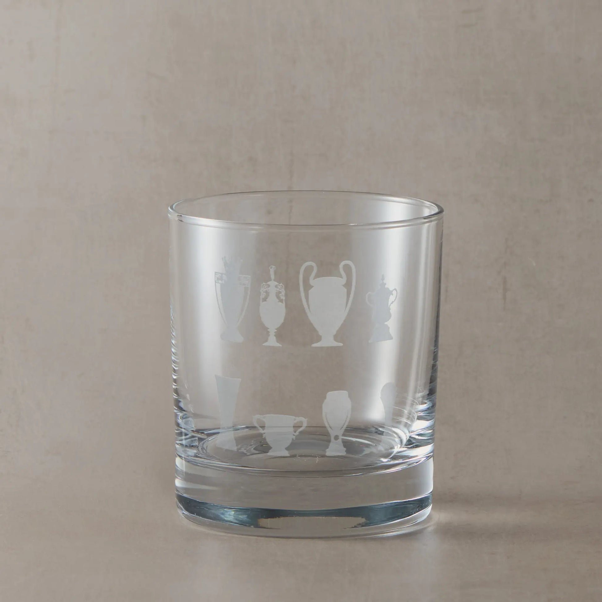 Personalised whisky glass engraved with honours wall eight trophy silhouettes photographed on a beige background