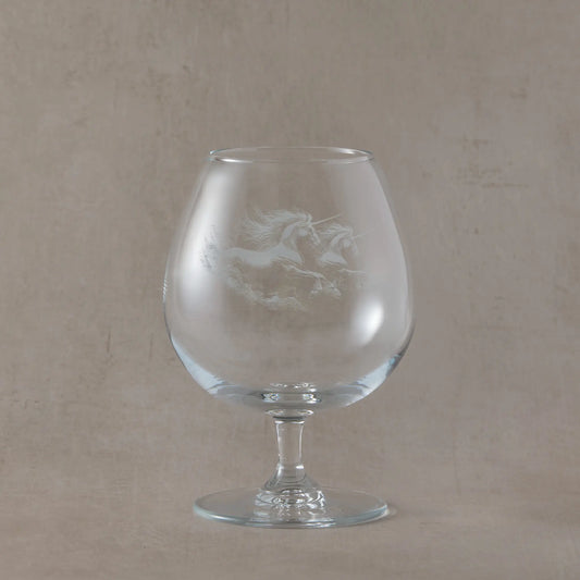 Clear brandy glass engraved with two galloping unicorns on a soft neutral background