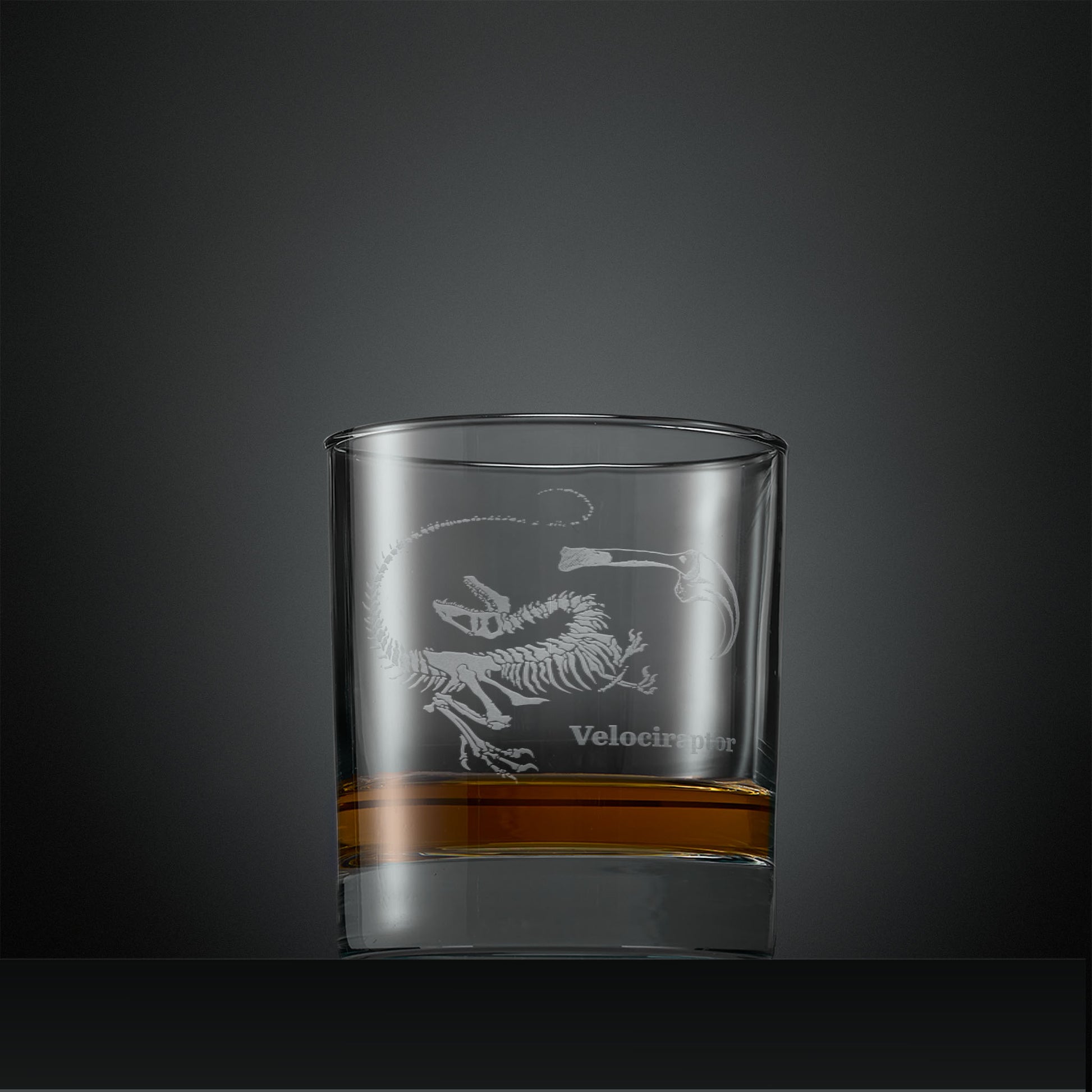 Engraved whisky glass with velociraptor fossil design