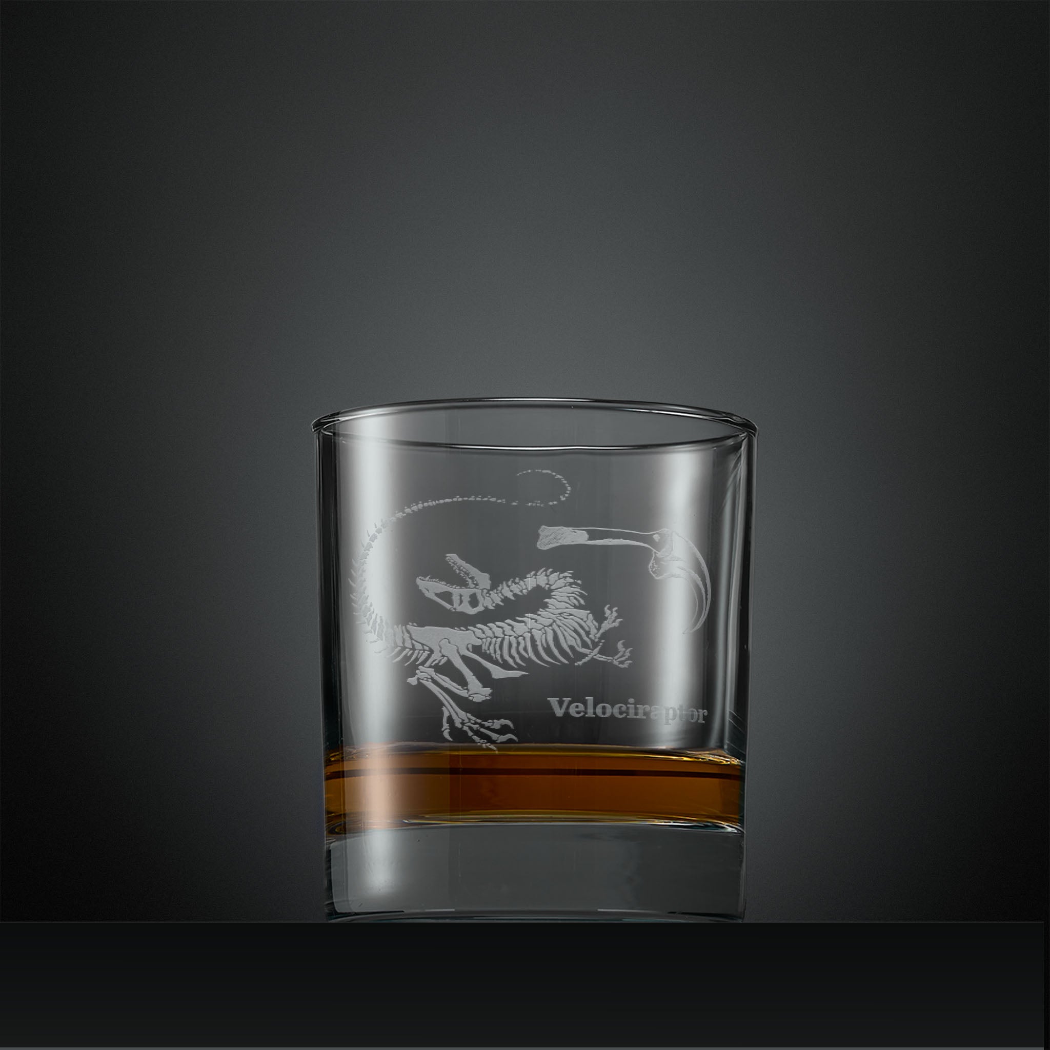 Engraved whisky glass with velociraptor fossil design