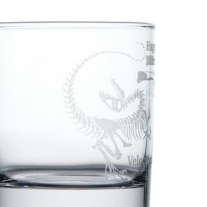 Close-up detail of a personalised whisky glass engraved with a Velociraptor dinosaur fossil