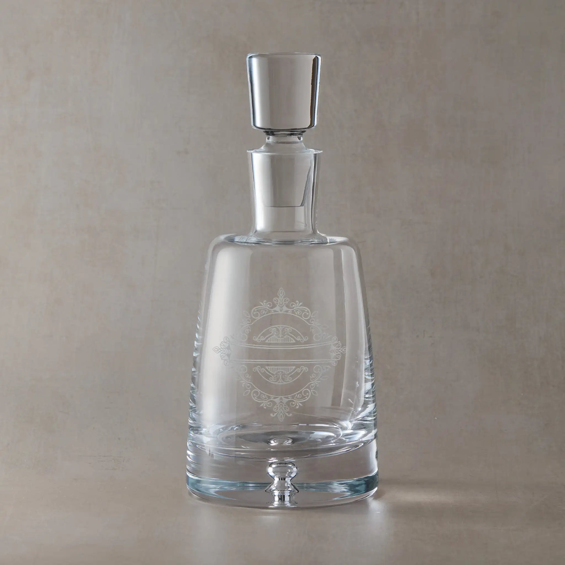 Handmade decanter engraved with venetian lacework design shown on a beige background