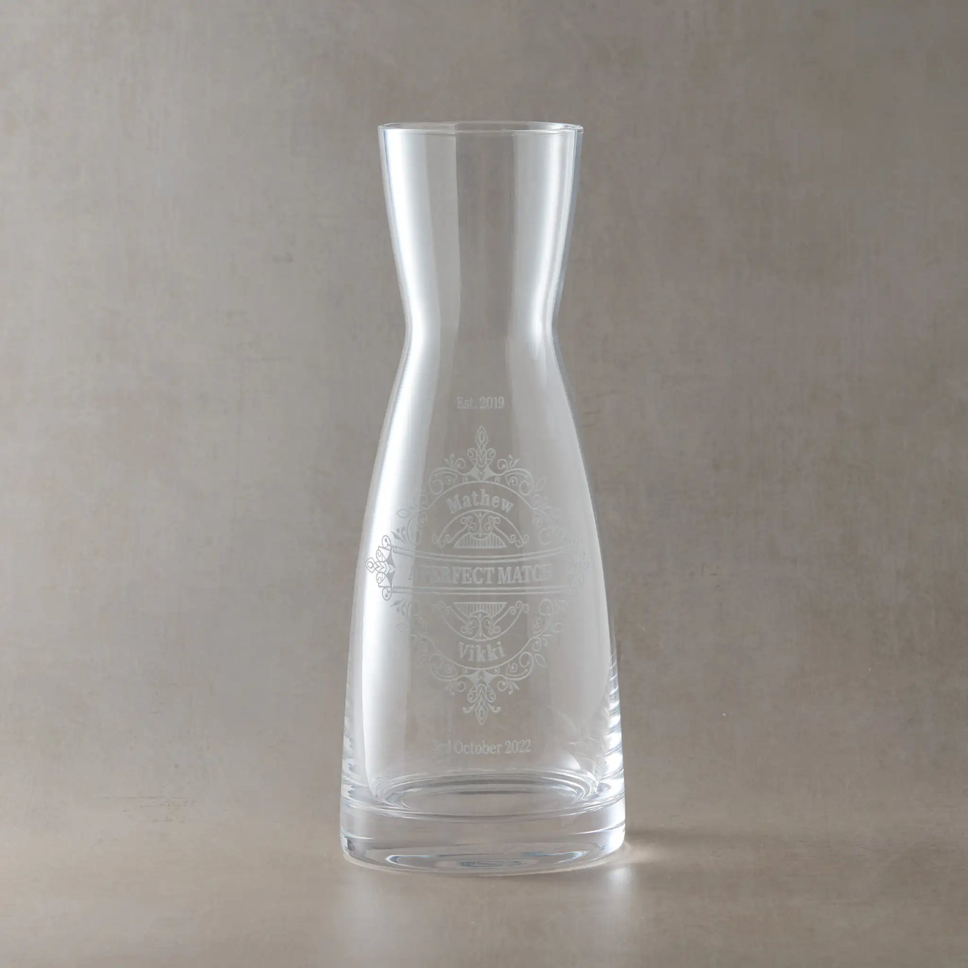 Personalised carafe with engraved venetian lace design and bride and grooms names and wedding date on a beige background