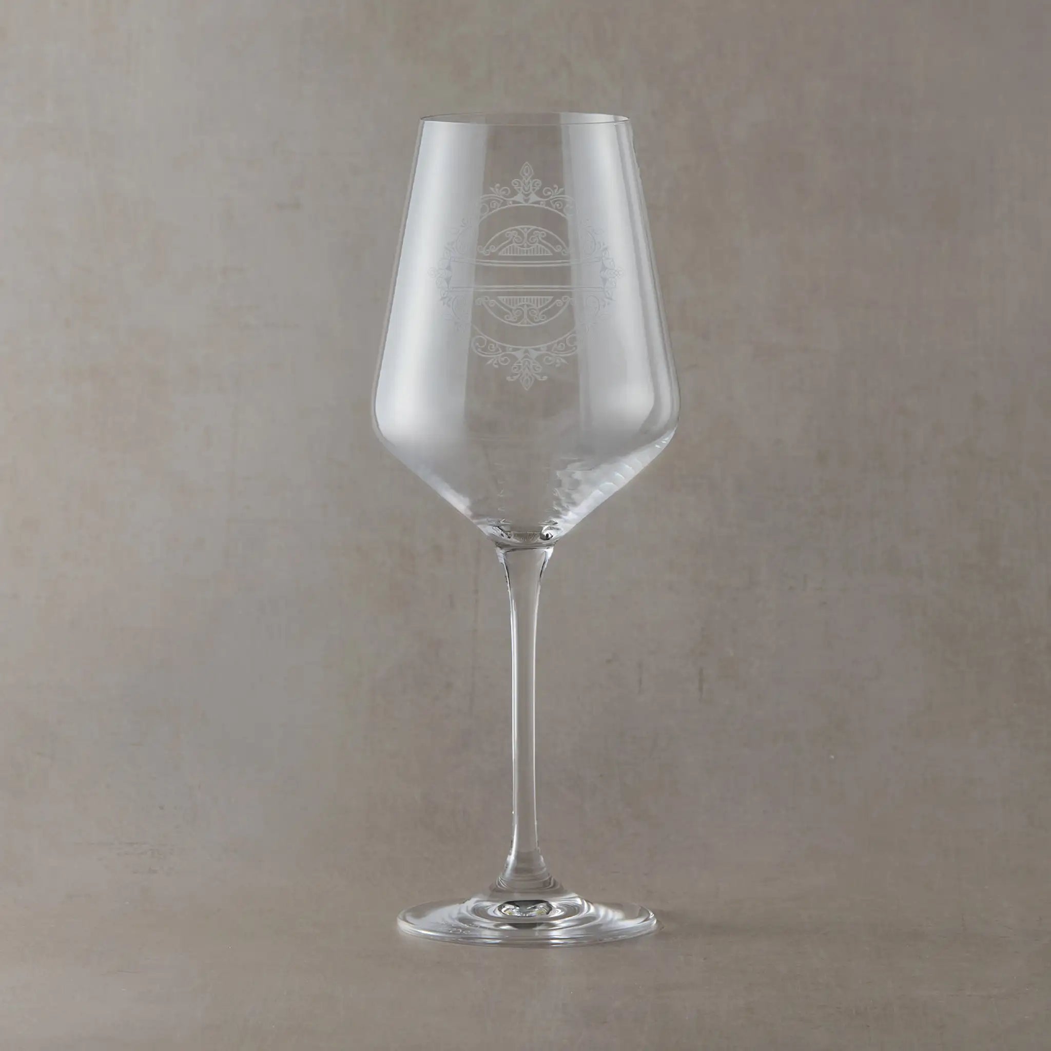 Clear wine glass with engraved bridal party design on a beige background