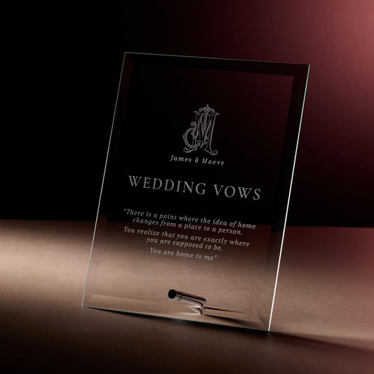 Glass display plaque with engraved monogram and wedding vows, photographed on a dark, softly lit background