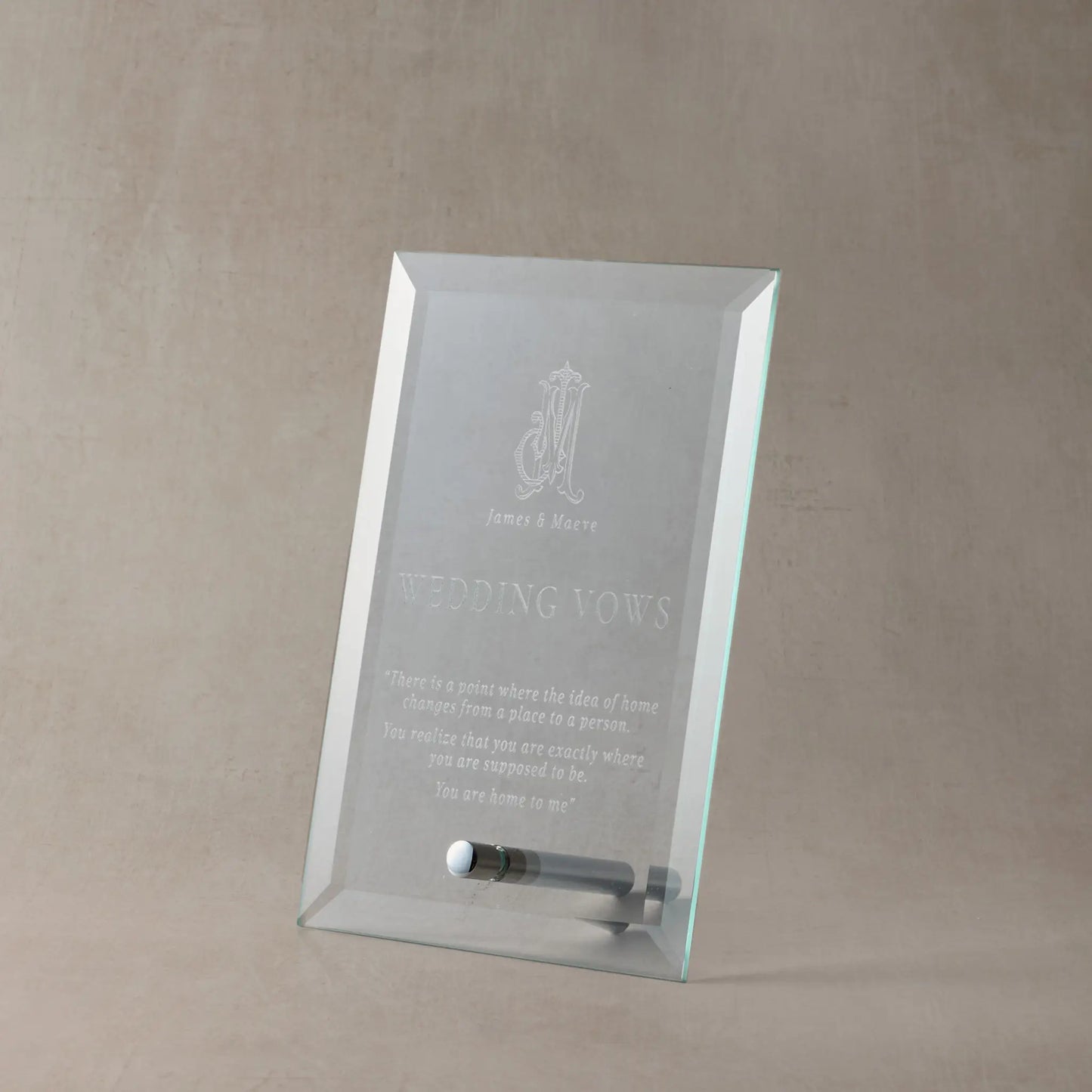 Engraved glass display plaque featuring wedding vows, photographed upright on a neutral stone-toned background with soft shadowing to highlight the engraving clarity