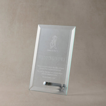 Engraved glass display plaque featuring wedding vows, photographed upright on a neutral stone-toned background with soft shadowing to highlight the engraving clarity