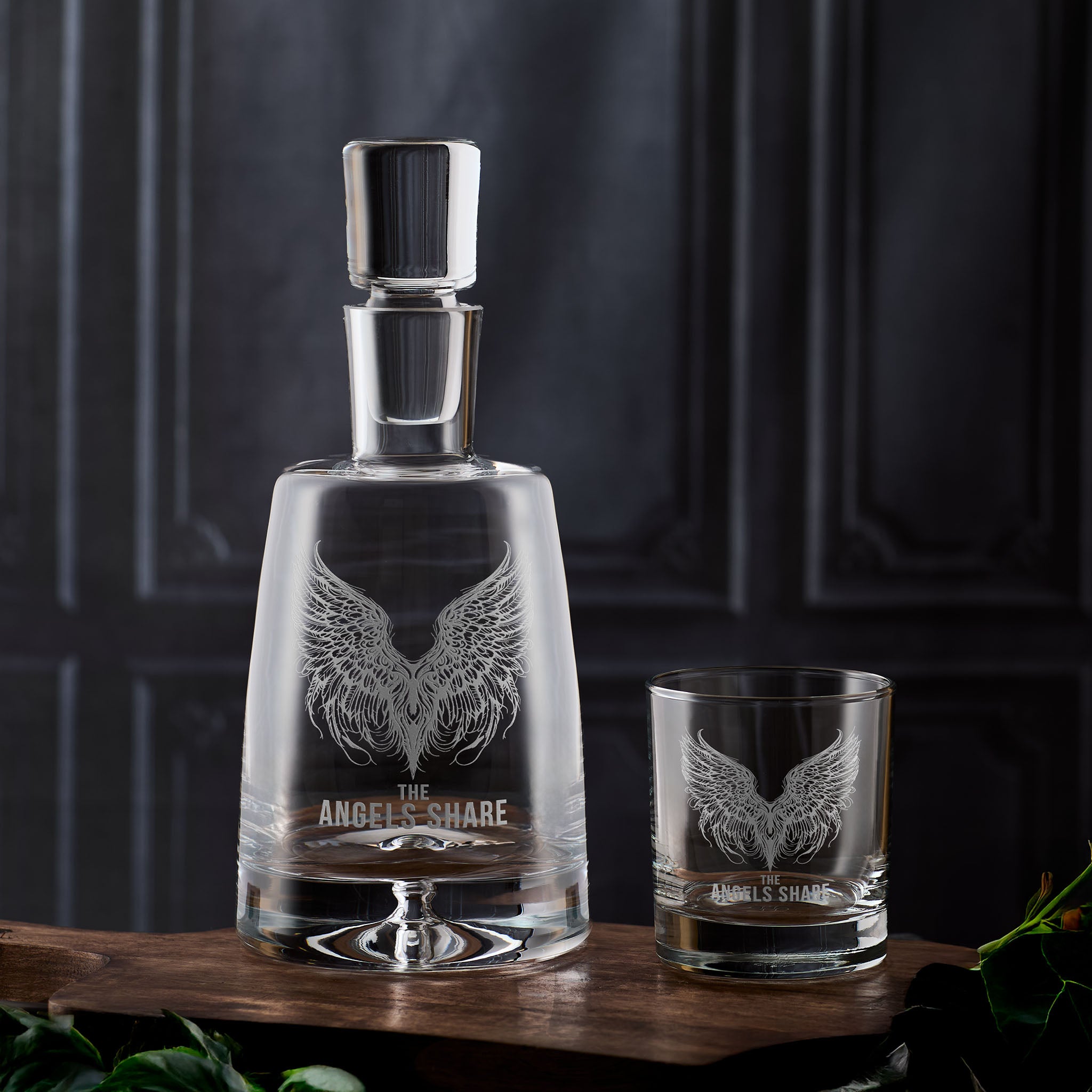 Glass decanter and whisky glass with 'The Angel's Share' engraving on a dark background 