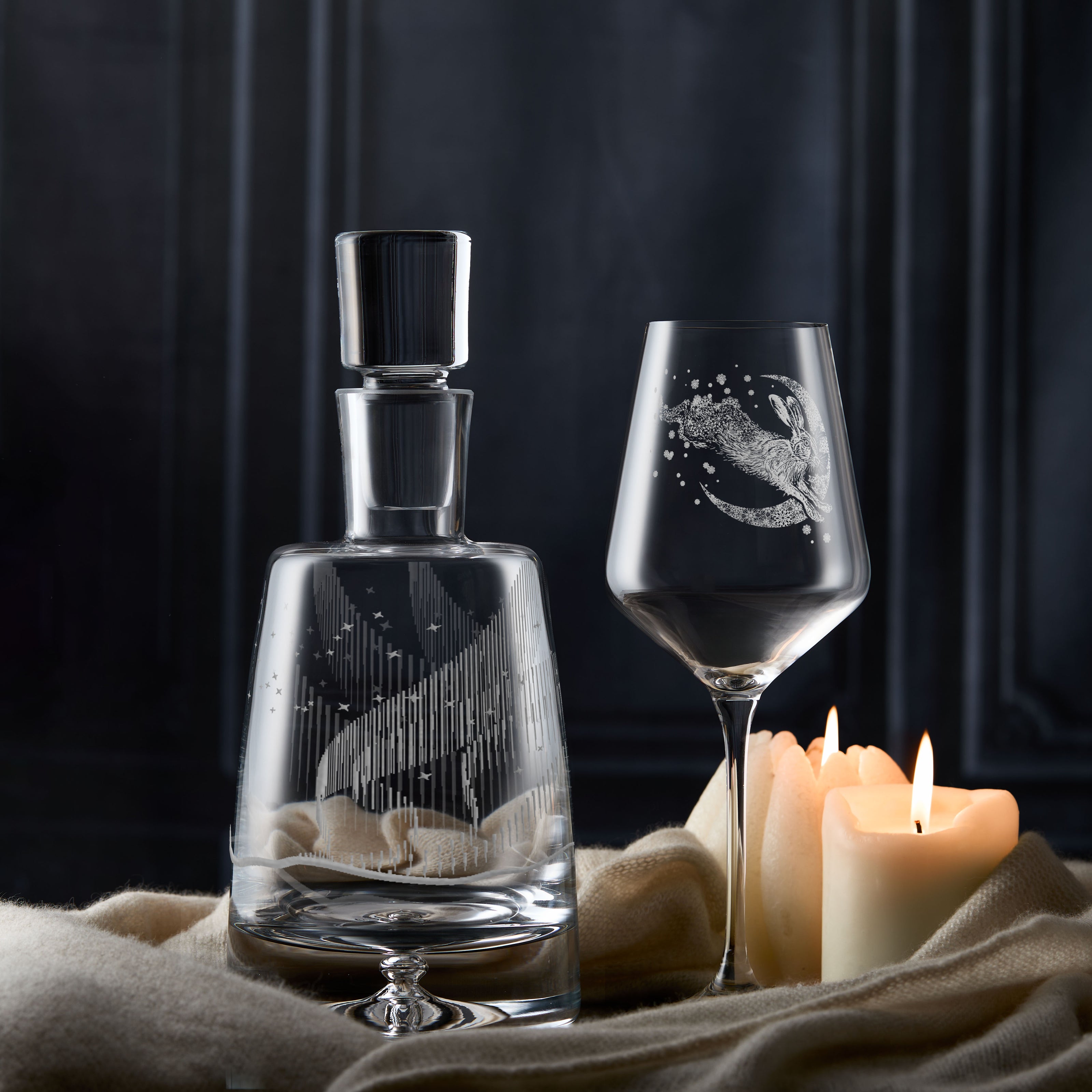 Aurora Borealis decanter and snow hare engraved wine glass on a dark background.