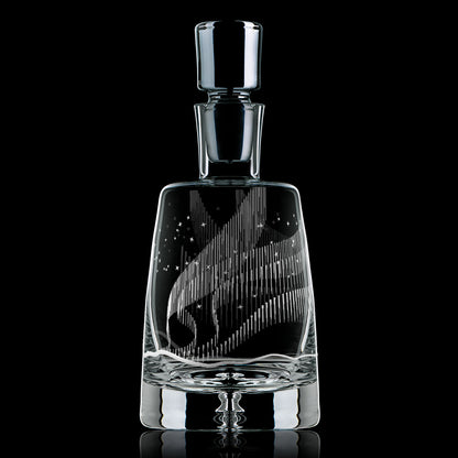 Glass decanter engraved with an Aurora Borealis design on a black background.