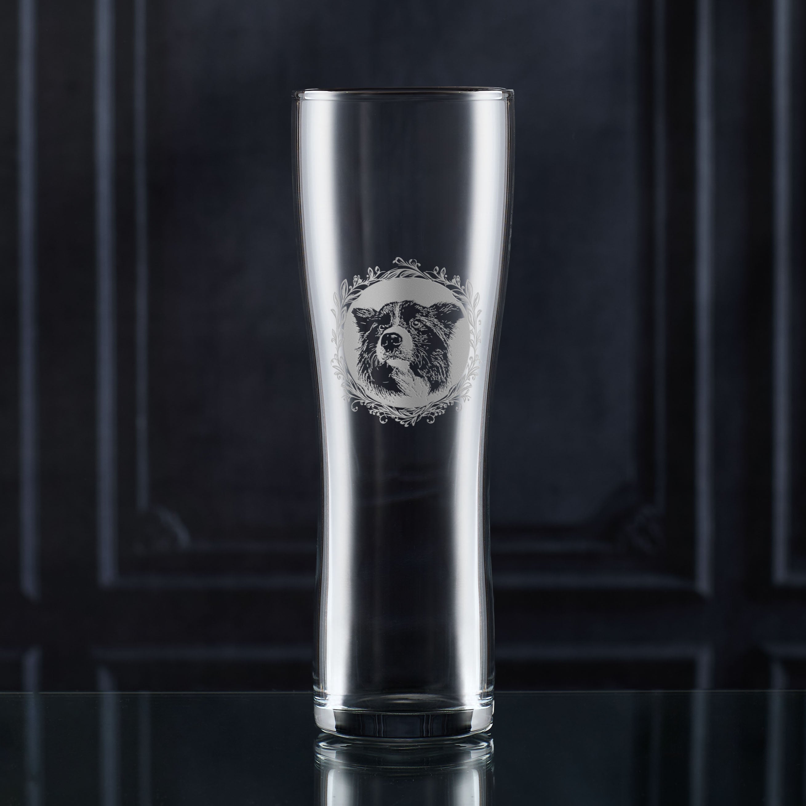 Pint glass engraved with a Border Collie illustration on a dark background.