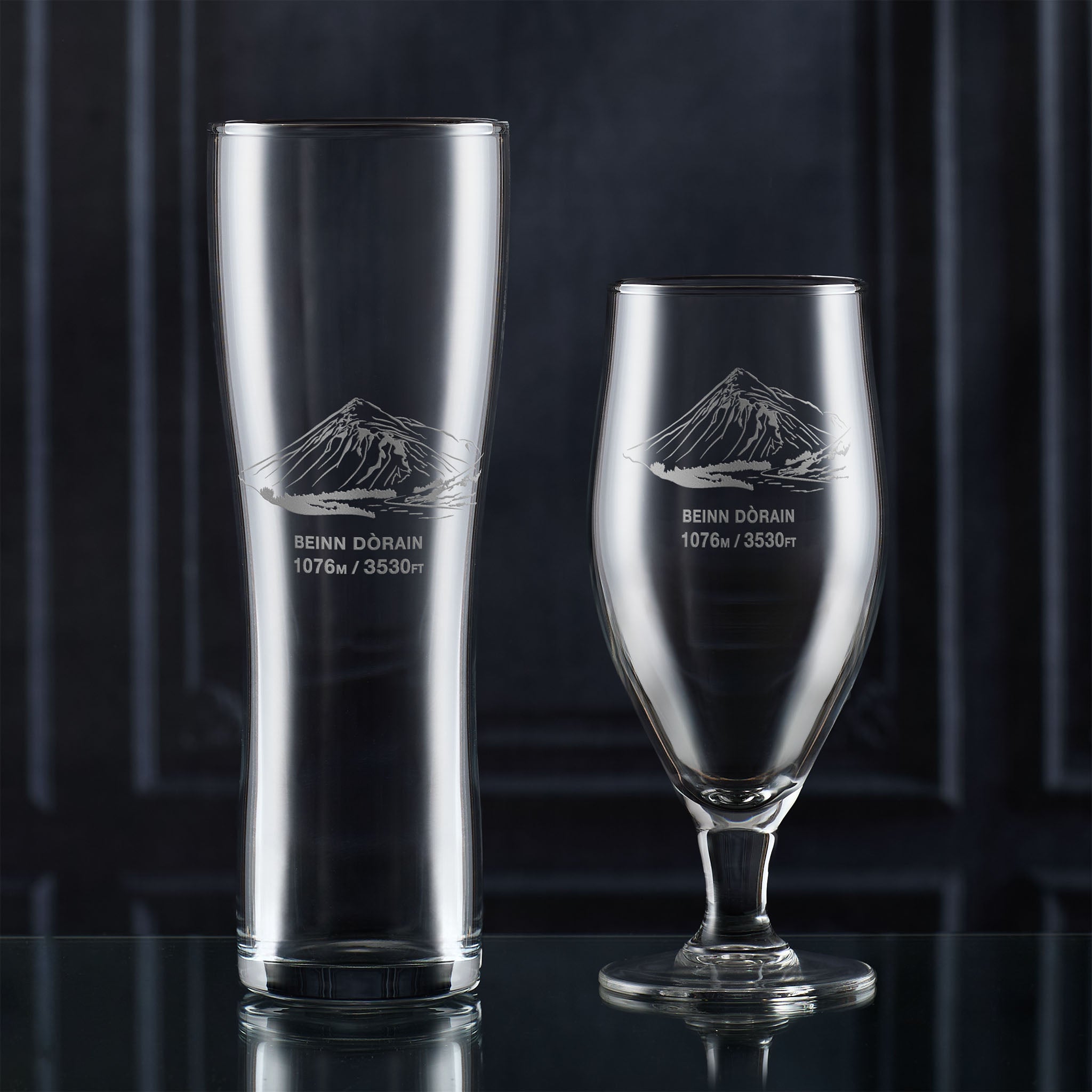 Pint and stemmed beer glasses engraved with Beinn Dorain, shown together on a dark background