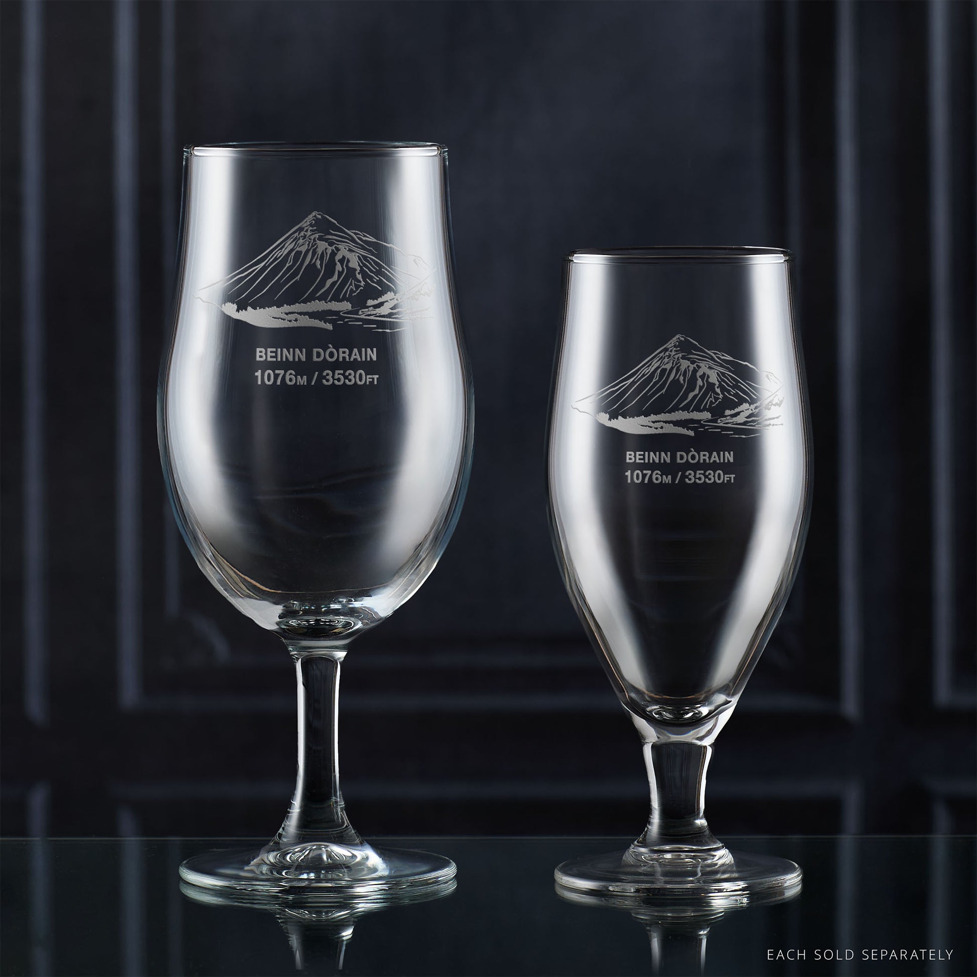 Pair of stemmed beer glasses engraved with Beinn Dorain, photographed on a reflective surface