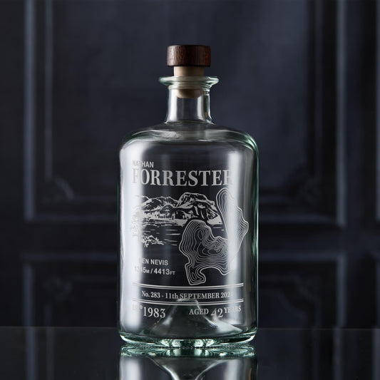 Glass decanter bottle with engraved Ben Nevis design and personalised text on a dark background