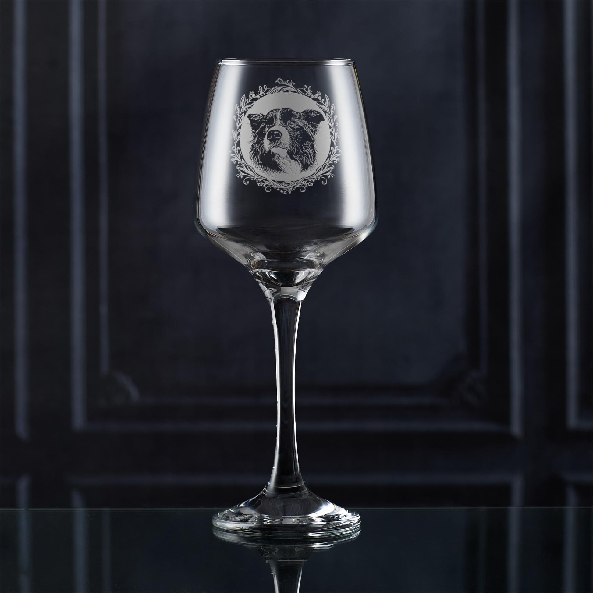 Wine glass with engraved border collie portrait in circular frame with leafy garland