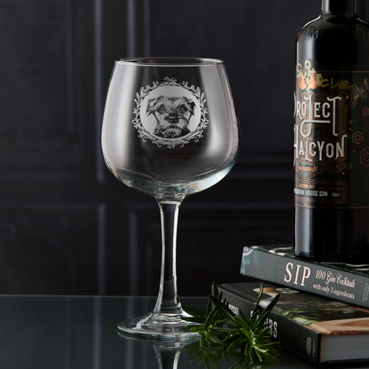 Hand-engraved Border Terrier gin glass displayed in front of dark wooden panelling, showing a straight-on portrait with leafy garland design by Just The Ticket.