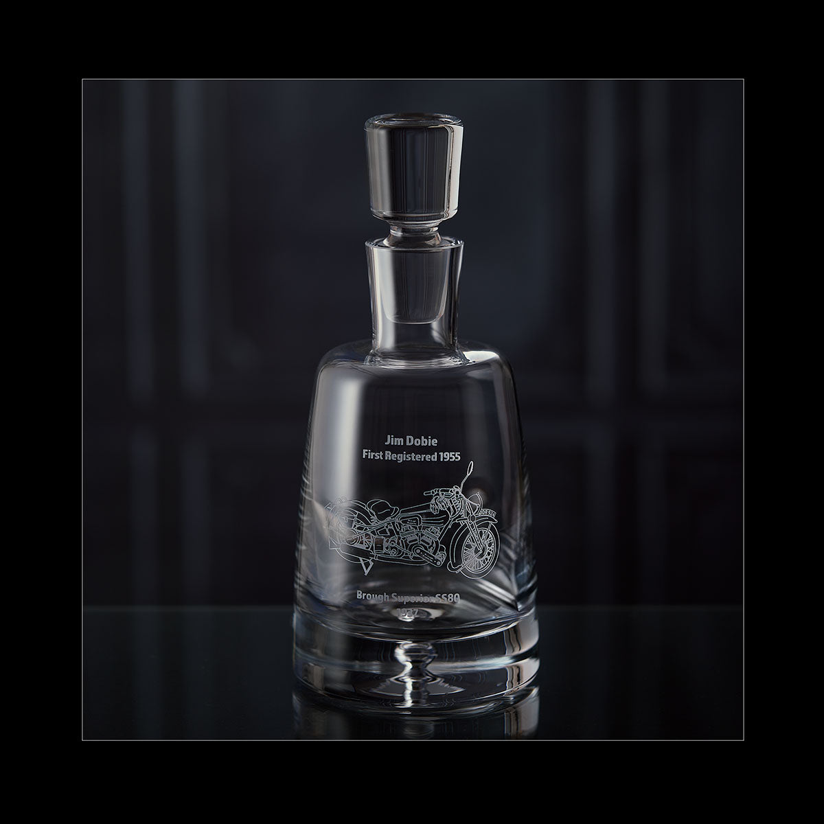 Whisky decanter with engraved motorcycle design on a dark background
